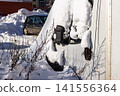 Snow-covered truck cabin hibernates under thick winter white blanket. Sun casts long shadows across the dormant vehicle, awaiting spring's thaw 141556364
