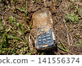 Old push-button telephone that has been lying in the ground for a long time 141556374