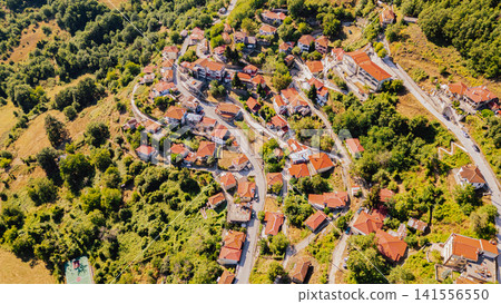 Top down aerial view of traditional Greek mountain village with red tile roof houses nestled in lush forest hills near Lake Plastiras Karditsa Thessaly Greece Top down aerial view of traditional Greek mountain village with red tile roof houses nestled in lush forest hills near Lake Plastiras Karditsa Thessaly Greece 141556550