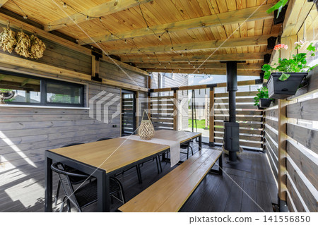 Cozy Covered Wooden Terrace with Dining Table and Stove Cozy Covered Wooden Terrace with Dining Table and Stove 141556850