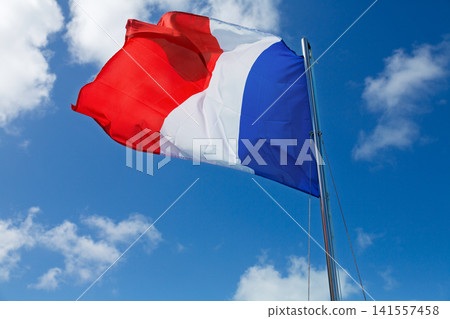 French flag waving against blue sky with white clouds 141557458