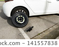 a temporary spare wheel resting on the car, ready to be changed 141557838