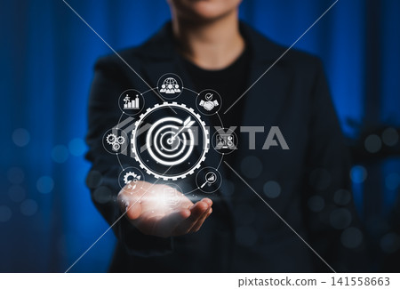 Business Goals and Target Success Strategy Concept. Businessperson presents target icon surrounded by symbols representing performance, objectives, growth, teamwork, analytics, and success metrics. Business Goals and Target Success Strategy Concept. Businessperson presents target icon surrounded by symbols representing performance, objectives, growth, teamwork, analytics, and success metrics. 141558663