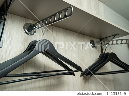 Black hangers arranged on a metal rack in a storage space Black hangers arranged on a metal rack in a storage space 141558849