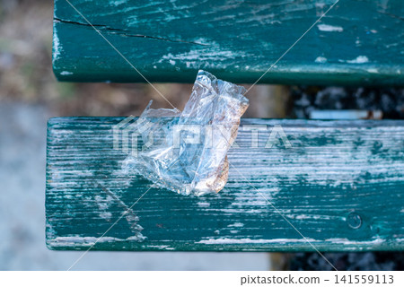 Plastic bag on worn wooden bench 141559113
