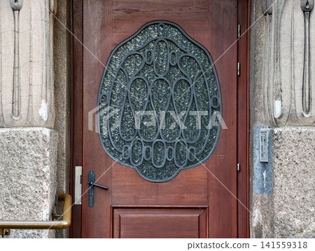 Ornate wooden entrance door with decorative wrought iron grille Ornate wooden entrance door with decorative wrought iron grille 141559318