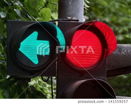 Traffic signal with green left arrow and red stop light against leafy background Traffic signal with green left arrow and red stop light against leafy background 141559357