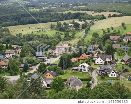Hillside village with scattered houses and green farmland Hillside village with scattered houses and green farmland 141559385