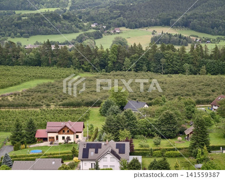 Rural hillside neighborhood with houses, orchards, and forested valley Rural hillside neighborhood with houses, orchards, and forested valley 141559387
