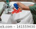 Child Playfully Washing a Water Gun at a Bathroom Sink 141559430
