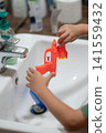 Bright bathroom scene with a child playing with a water gun in summer light 141559432