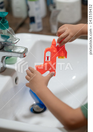 Bright bathroom scene with a child playing with a water gun in summer light Bright bathroom scene with a child playing with a water gun in summer light 141559432