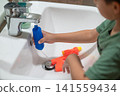 Playful boy experimenting with water toys in a kitchen sink 141559434