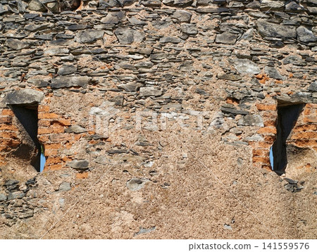 Weathered stone and mortar wall with narrow openings Weathered stone and mortar wall with narrow openings 141559576