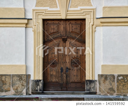 Ornate wooden double door in historic stone entrance Ornate wooden double door in historic stone entrance 141559592