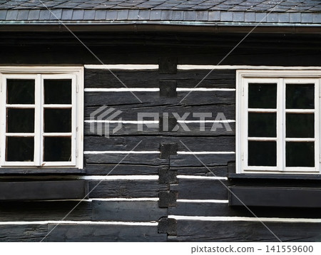 Black timber cottage facade with white framed windows and shutters 141559600