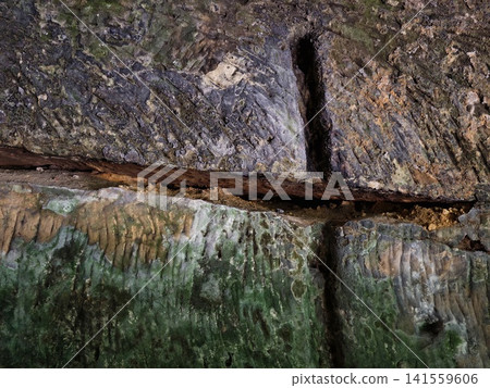 Close-up of mossy cave wall with mineral streaks and fissures Close-up of mossy cave wall with mineral streaks and fissures 141559606
