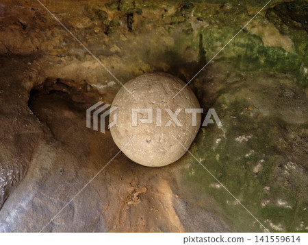 Round stone sphere resting in mossy cave niche Round stone sphere resting in mossy cave niche 141559614