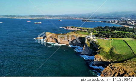 Experience the stunning coastal view with a lighthouse and a captivating green landscape Experience the stunning coastal view with a lighthouse and a captivating green landscape 141559847