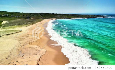 Breathtaking Aerial View of a Pristine Beach Next to Turquoise Waves and Clear Skies 141559890