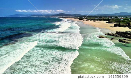 Experience the serene coastal view featuring gentle waves crashing against a sandy beach Experience the serene coastal view featuring gentle waves crashing against a sandy beach 141559899