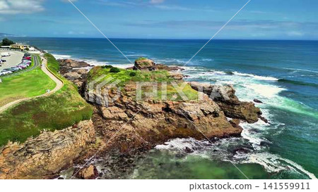 A Stunning Coastal Landscape Showcasing a Rocky Shore and Waves Crashing on the Beach 141559911