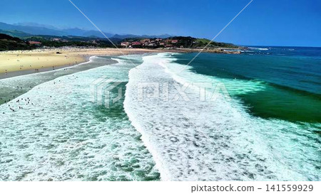 Experience the breathtaking beauty of beach waves crashing gently under a clear blue sky Experience the breathtaking beauty of beach waves crashing gently under a clear blue sky 141559929