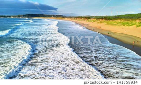 Experience a stunning coastal view where waves crash gently onto a beautiful sandy beach Experience a stunning coastal view where waves crash gently onto a beautiful sandy beach 141559934