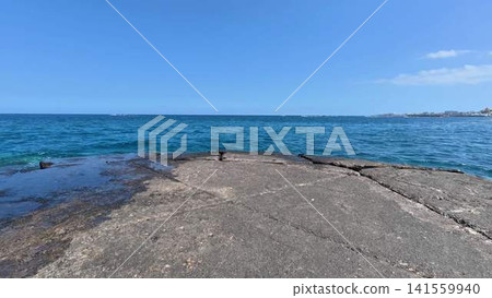 Enjoy Tranquil Ocean Waves lapping against Rocky Shoreline under a Clear Blue Sky Enjoy Tranquil Ocean Waves lapping against Rocky Shoreline under a Clear Blue Sky 141559940