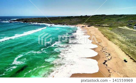 Experience the stunning aerial view of a coastal beach and its inviting waves captured by a drone Experience the stunning aerial view of a coastal beach and its inviting waves captured by a drone 141559969