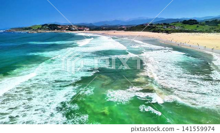 An aerial view shows a stunning coastal beach with gentle waves and clear, pristine water An aerial view shows a stunning coastal beach with gentle waves and clear, pristine water 141559974