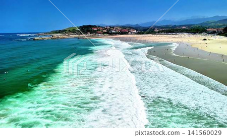 This vibrant and picturesque coastal scene features dynamic waves crashing onto a sunlit beach This vibrant and picturesque coastal scene features dynamic waves crashing onto a sunlit beach 141560029