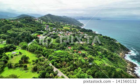 This aerial view showcases a lush green coastal landscape, blending nature and adventure This aerial view showcases a lush green coastal landscape, blending nature and adventure 141560132