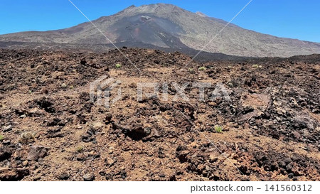 Experience the stunning volcanic landscape under a clear blue sky, captivating all visitors 141560312