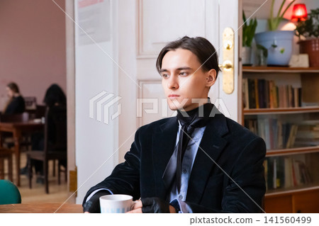Aristocrat man with scarf and gloves holding cup in interior. Historical style portrait of elegant gentleman. Refined fashion aesthetic, noble look, classic male character study. Aristocrat man with scarf and gloves holding cup in interior. Historical style portrait of elegant gentleman. Refined fashion aesthetic, noble look, classic male character study. 141560499