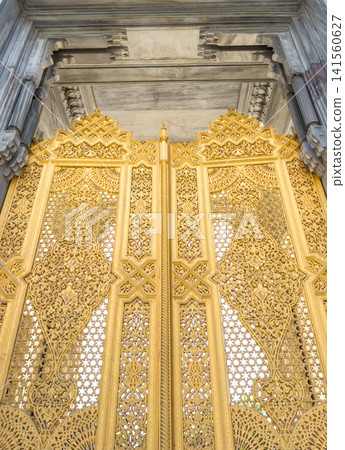 Ornate golden gate with intricate carvings in traditional architectural style Ornate golden gate with intricate carvings in traditional architectural style 141560627