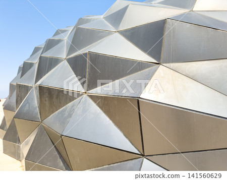 Geometric metallic facade with angular patterns under clear blue sky Geometric metallic facade with angular patterns under clear blue sky 141560629