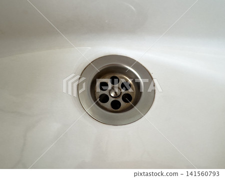Close-up view of stainless steel sink drain in white basin Close-up view of stainless steel sink drain in white basin 141560793