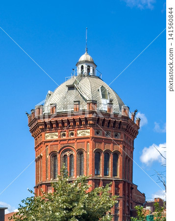 Historic red brick tower with a domed roof and decorative elements against a clear blue sky in an urban setting Historic red brick tower with a domed roof and decorative elements against a clear blue sky in an urban setting 141560844