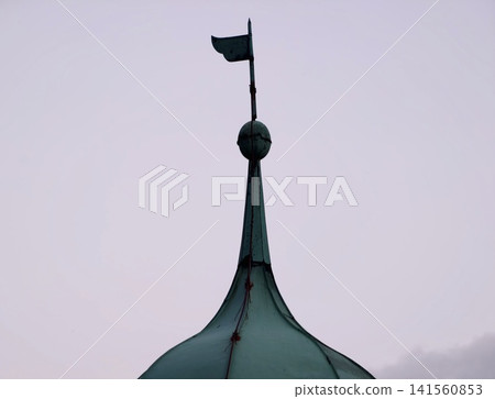 Copper spire highlighted. Architectural finial in copper with subtle sky gradient and peaceful ambiance Copper spire highlighted. Architectural finial in copper with subtle sky gradient and peaceful ambiance 141560853