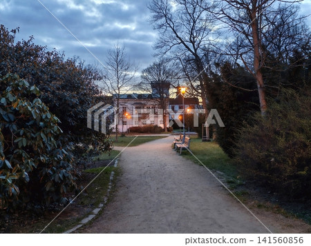 Evening garden scene. Soft evening light gleams on peaceful walkway guiding to inviting manor door 141560856