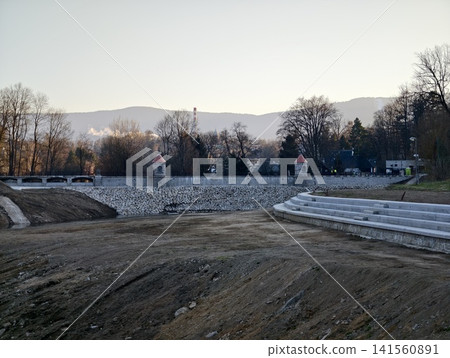 An aged water reservoir with nearby hills. Drained reservoir showcasing steps and eroded banks An aged water reservoir with nearby hills. Drained reservoir showcasing steps and eroded banks 141560891