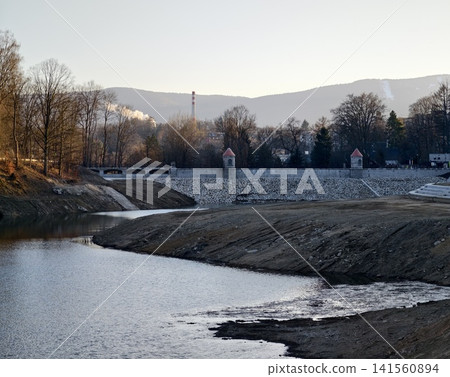Concrete terraces and twin towers. Industrial scene with control embankment at sunset and hills Concrete terraces and twin towers. Industrial scene with control embankment at sunset and hills 141560894