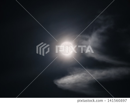 Luminous moon surrounded by floating clouds casts gentle silver light over tranquil night atmosphere Luminous moon surrounded by floating clouds casts gentle silver light over tranquil night atmosphere 141560897