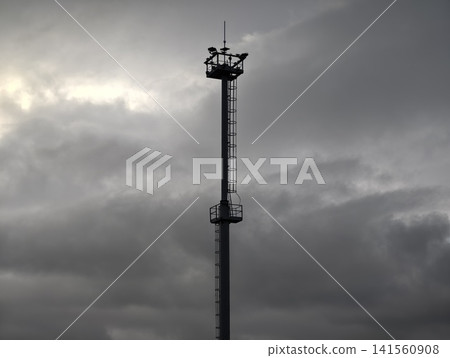 Industrial tower solitude. Weathered industrial structure stands vigilant under turbulent sky Industrial tower solitude. Weathered industrial structure stands vigilant under turbulent sky 141560908