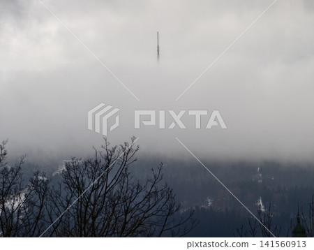 Silent fog surrounds tall mountain peak. Gray shadows envelop peaceful woodland and towering summit Silent fog surrounds tall mountain peak. Gray shadows envelop peaceful woodland and towering summit 141560913