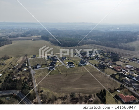 Scenic aerial view with homes. Elevated perspective showing rural homes and patchwork landscape Scenic aerial view with homes. Elevated perspective showing rural homes and patchwork landscape 141560947