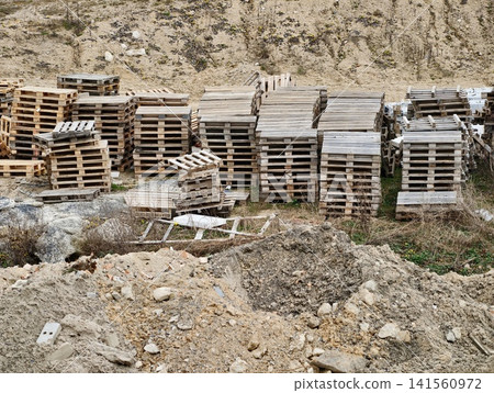 Rustic pallets awaiting reuse. Organized rows of aged pallets on dusty quarry lot ready for reuse Rustic pallets awaiting reuse. Organized rows of aged pallets on dusty quarry lot ready for reuse 141560972