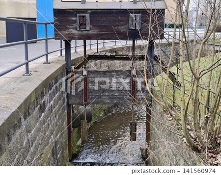 Abandoned industrial canal facility featuring weathered control box and overgrown surroundings Abandoned industrial canal facility featuring weathered control box and overgrown surroundings 141560974