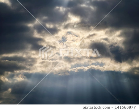 Sun rays cut through dark skies. Intense sunlight pierces ominous stormy cloud formations dramatically Sun rays cut through dark skies. Intense sunlight pierces ominous stormy cloud formations dramatically 141560977